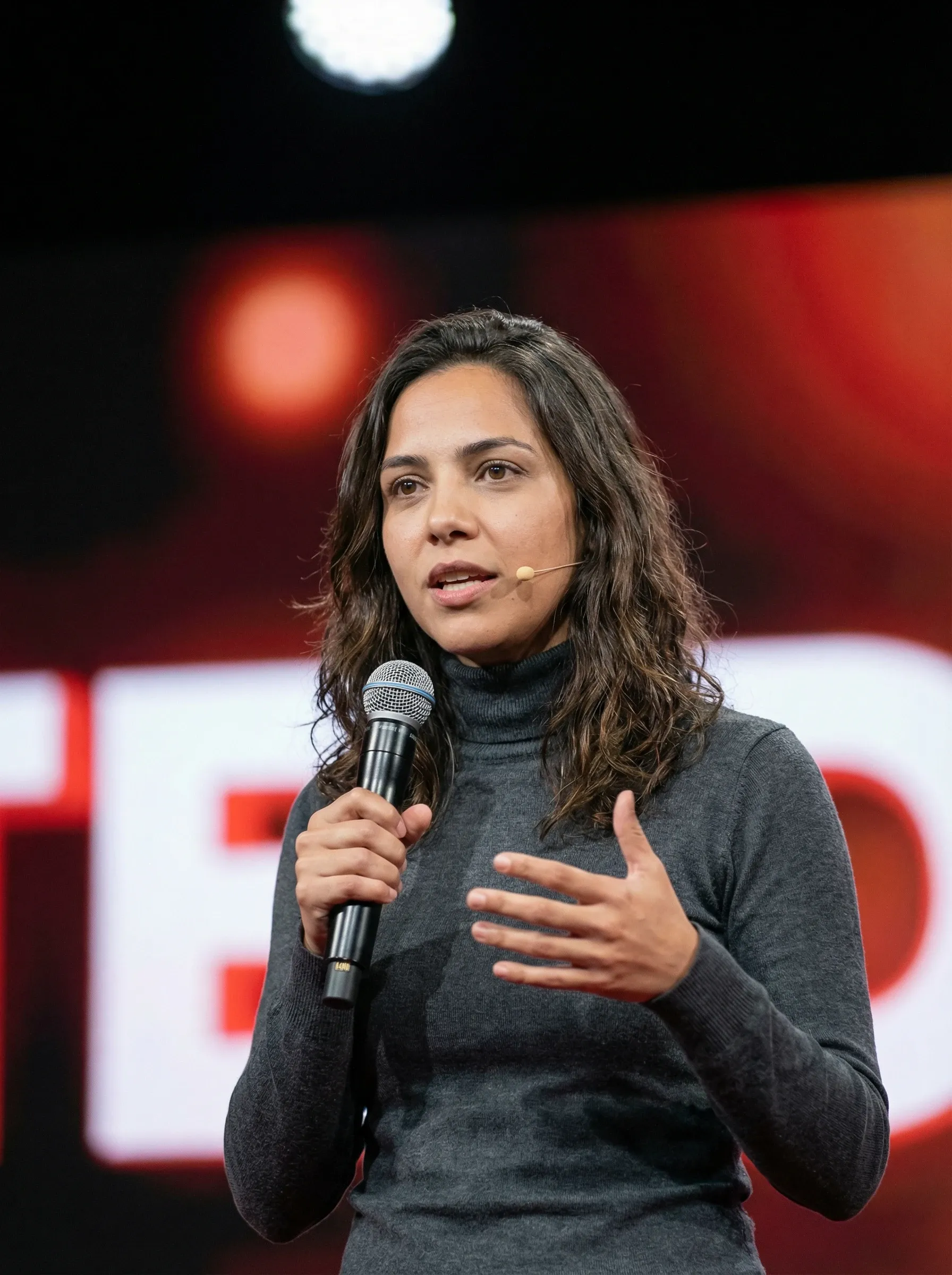 AI LinkedIn headshot — woman in a gray turtleneck holding a microphone on stage